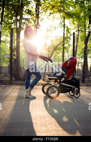 Mother walking child in a pram in the park