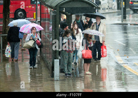 Wimbledon London,UK. 24th August 2015.  Pedestrians and shoppers sheltering in a bus shelter from the rain in Wimbledon town centre on a wet day in London Credit:  amer ghazzal/Alamy Live News Stock Photo