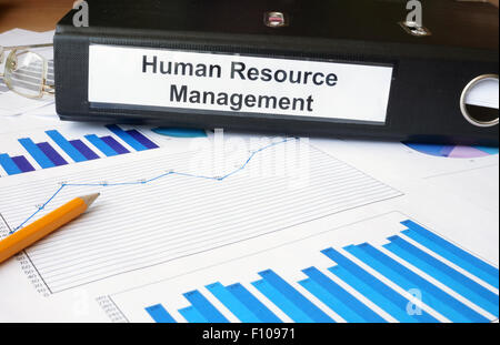 Graphs and file folder with label Human Resource Management. Business concept. Stock Photo