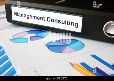 Graphs and file folder with label Management Consulting. Business concept. Stock Photo