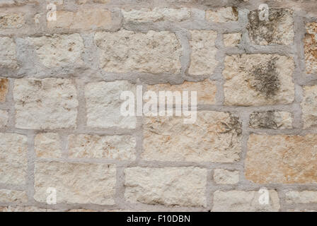 Beige and cream stones in an outdoor wall with thick grout Stock Photo