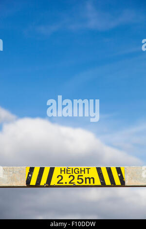 Part of a height restriction metal barrier to a car park, showing the limit as 2.25m in yellow and black. Stock Photo