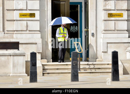 London, England, UK. Security guard outside the Cabinet Office, 70 Whitehall, holding an umbrella on a sunny day in August Stock Photo