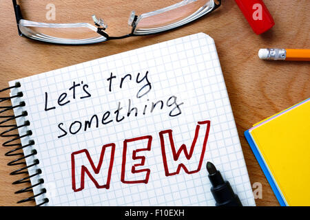 Notepad with let’s try something new  on office wooden table. Stock Photo