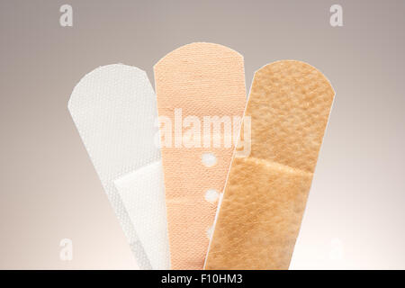 Set of three medical adhesive plasters with different purposes and textures, on gradient grey to white background Stock Photo