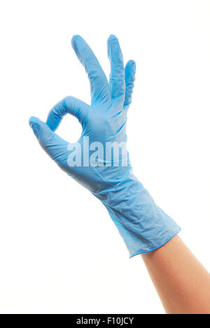 Close up of female doctor's hand in blue sterilized surgical glove showing OK sign against white background Stock Photo