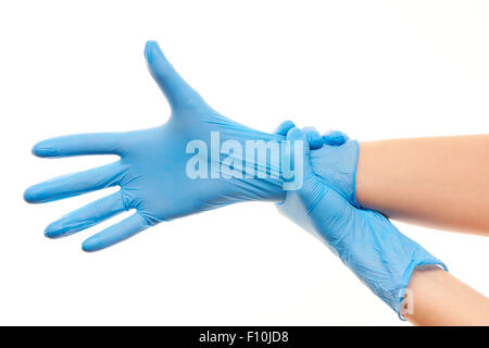 Close up of female doctor's hands putting on blue sterilized surgical gloves against white background Stock Photo