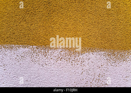 closeup of a rustic plastered wall painted in two colors, dark yellow and white, to use as a background Stock Photo