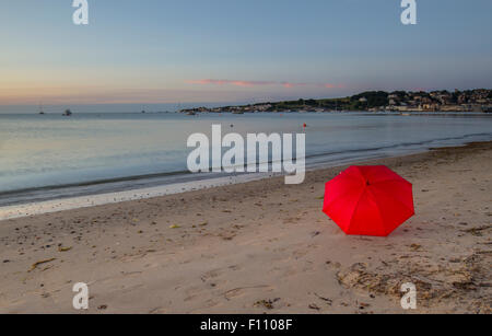 sunrise on Swanage bay with red umbrella Stock Photo