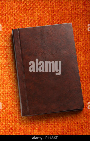 Blank closed notebook on orange fabric background Stock Photo