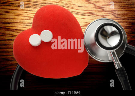 Red heart, stethoscope and pills on wooden background Stock Photo
