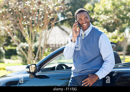 Black man talking on cell phone at convertible Stock Photo
