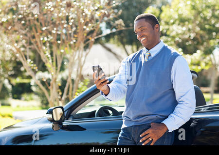 Black man using cell phone at convertible