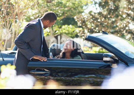 Gentleman opening door of convertible for woman Stock Photo