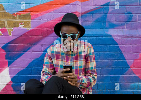 Black man using cell phone near colorful wall Stock Photo