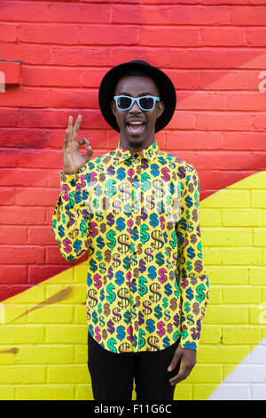 Black man in sunglasses making okay sign near colorful wall Stock Photo