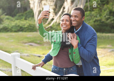 Couple taking selfies at fence Stock Photo