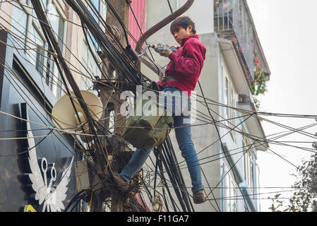 Vietnam street cables, above a street in the Old Quarter in Hanoi an electrical engineer works amid a dense tangle of power lines, Vietnam Stock Photo