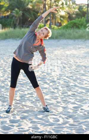 Caucasian woman stretching on beach Stock Photo