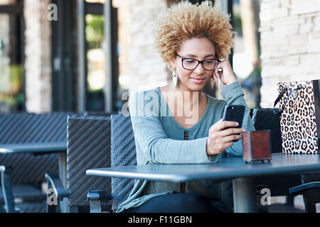 Black woman using cell phone at cafe Stock Photo