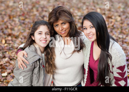 Hispanic mother and daughters hugging outdoors Stock Photo
