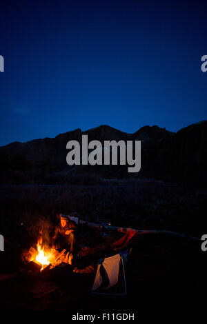Caucasian man sitting near campfire in remote landscape Stock Photo