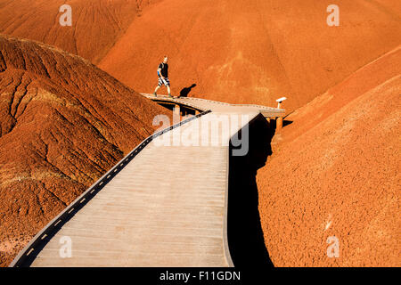 Caucasian hiker on wooden walkway in desert hills Stock Photo
