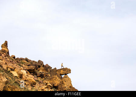 Caucasian hiker standing on sheer cliff boulder, Smith Rock State Park, Oregon, United States Stock Photo