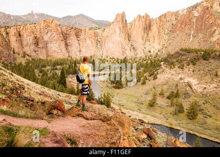 Caucasian hiker admiring hills and stream in desert landscape, Smith Rock State Park, Oregon, United States Stock Photo