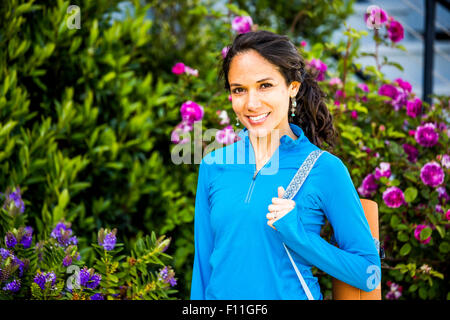 Hispanic woman carrying yoga mat in garden Stock Photo
