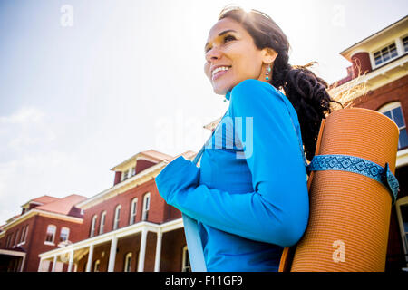 Hispanic woman carrying yoga mat outdoors Stock Photo