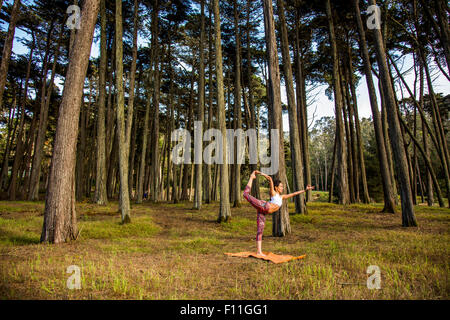 Hispanic woman practicing yoga in forest Stock Photo