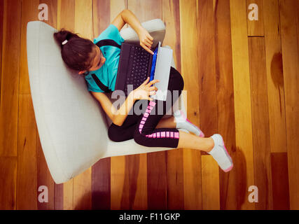 Overhead view of mixed race girl using digital tablet in armchair Stock Photo