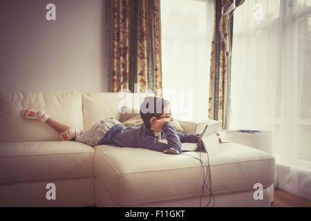 Mixed race boy using digital tablet on sofa Stock Photo