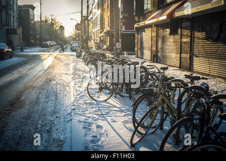 Bicycles parked in snow on city sidewalk, New York, New York, United States Stock Photo