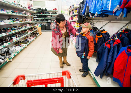 Caucasian grandmother and grandson shopping in clothing store Stock Photo