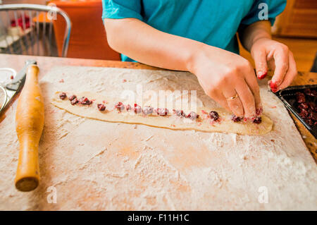 Caucasian woman placing berries in dough Stock Photo