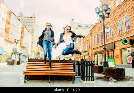 Women jumping for joy near bench