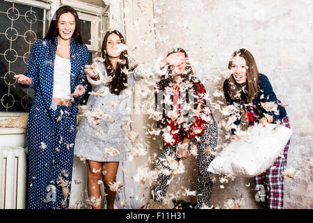 Caucasian women having pillow fight at sleepover Stock Photo