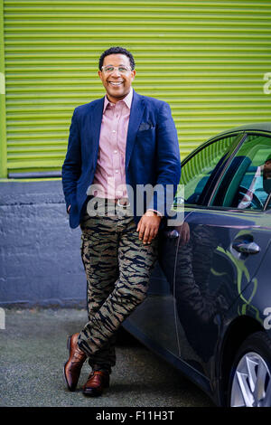 Stylish Mixed race businessman leaning on car Stock Photo