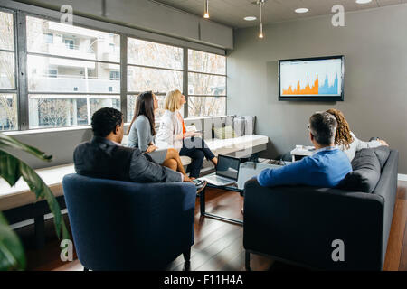 Business people watching presentation in office lounge Stock Photo