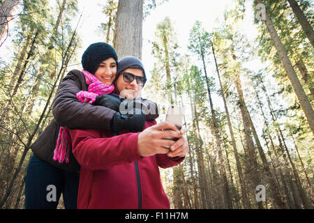 Hispanic teenage couple taking selfie in forest Stock Photo