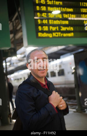Hispanic man standing on platform in train station Stock Photo