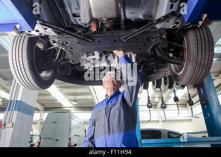 Older Hispanic mechanic repairing car in garage Stock Photo