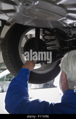 Older Hispanic mechanic repairing car in garage Stock Photo