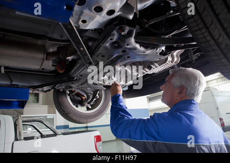 Older Hispanic mechanic repairing car in garage Stock Photo