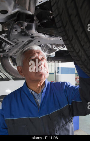 Older Hispanic mechanic repairing car in garage Stock Photo