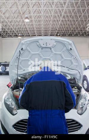 Older Hispanic mechanic repairing car in garage Stock Photo