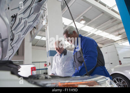 Older Hispanic mechanics repairing car in garage Stock Photo