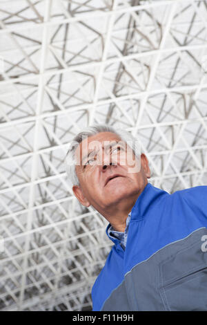 Low angle view of older Hispanic mechanic in warehouse Stock Photo
